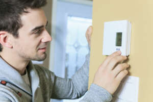 Pro Man Adjusting Room Temperature Shutterstock 252155254